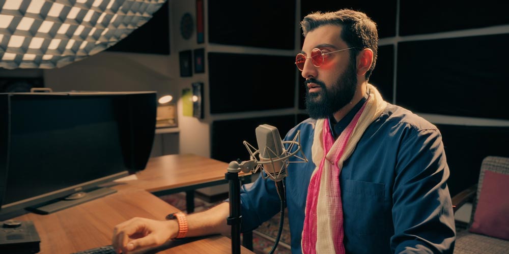 بهترین میکروفونها برای تولید محتوا در سال ۲۰۲۵: ۵ انتخاب هوشمندانه که شما را شگفتزده خواهد کرد 1 رضاصاد در استودیو پادکست، پشت میز و مقابل میکروفون نویمن TLM 103 در حال ضبط صدا RezaSaad in a podcast studio, sitting at a desk with a Neumann TLM 103 microphone recording audio